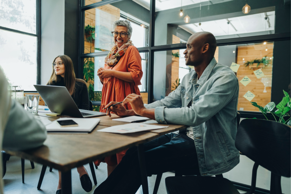 Underrepresented founders. Image shows 2 women and one man around a conference room table with papers and a computer on top.