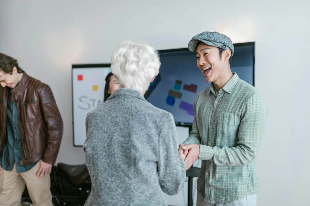 Man shaking woman's hand in front of screen with presentation