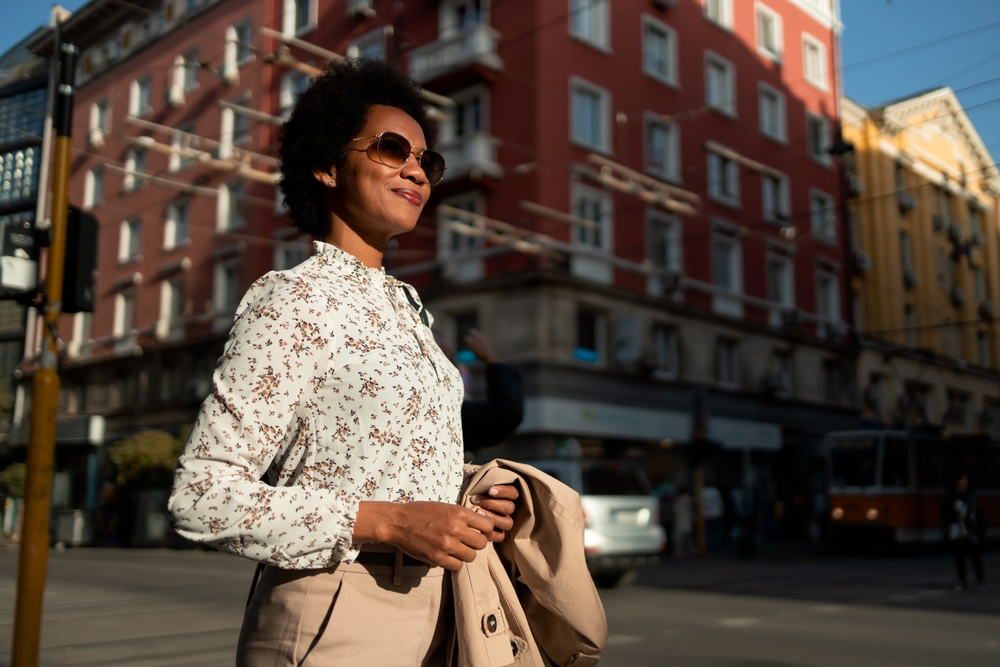 Female founder confidently walking and smiling in a downtown.